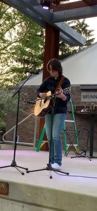 Matt Forte performing solo on an outdoor stage with an acoustic guitar.